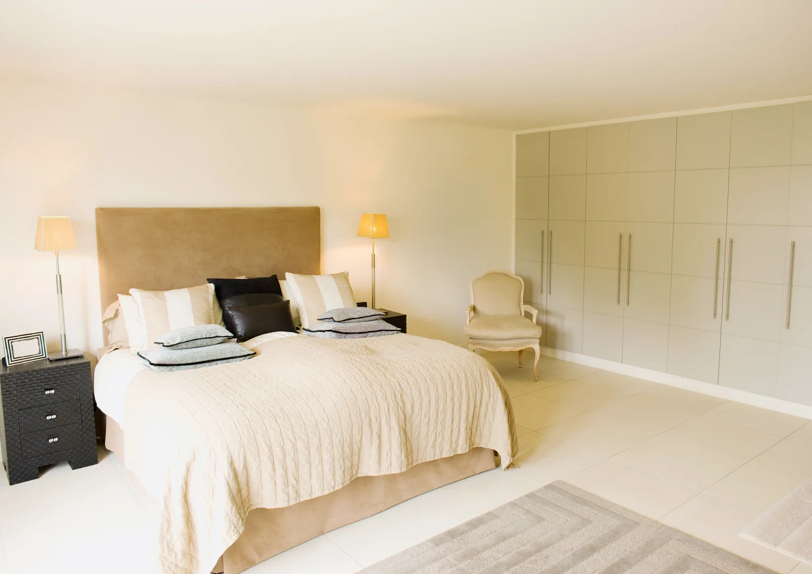 Neutral bedroom with a wide upholstered headboard and fitted wardrobes