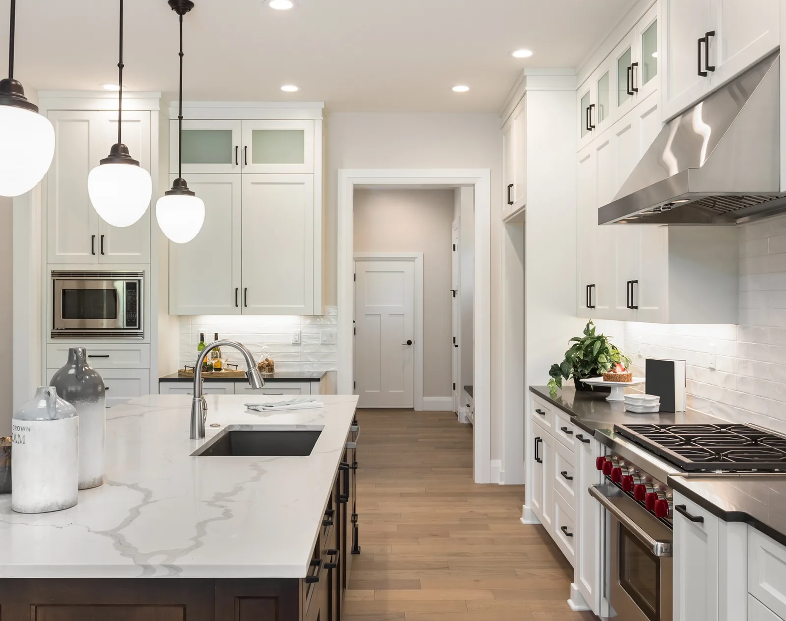 Galley kitchen in white with a quartz island and stainless range