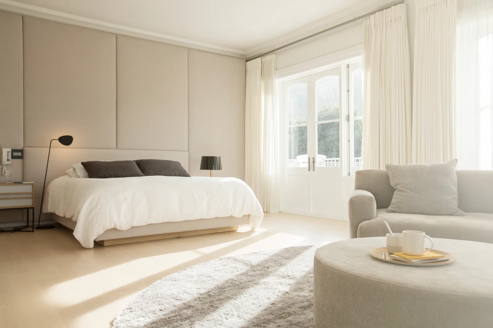 Sunlight falling in long bands across a bedroom floor through full-height glass doors
